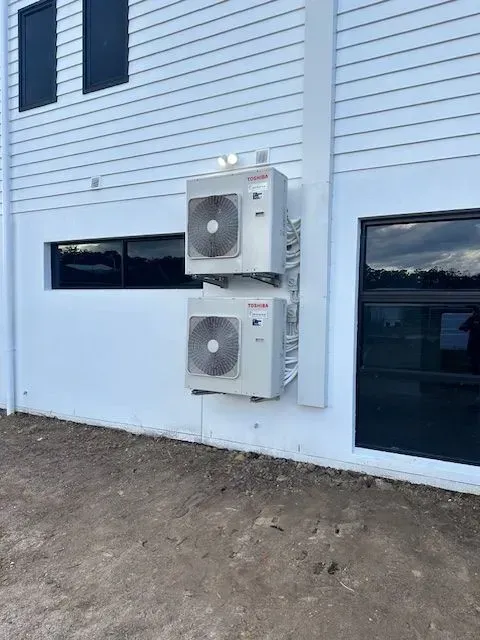 Two White Air Conditioning Units Mounted On A White Building Exterior