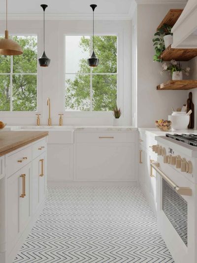 White kitchen with gold accents, featuring a window, stove, and floating shelves.