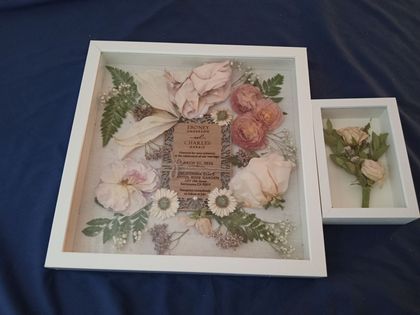 White and cream flowers arranged in a heart shape on a rustic board with green leaves