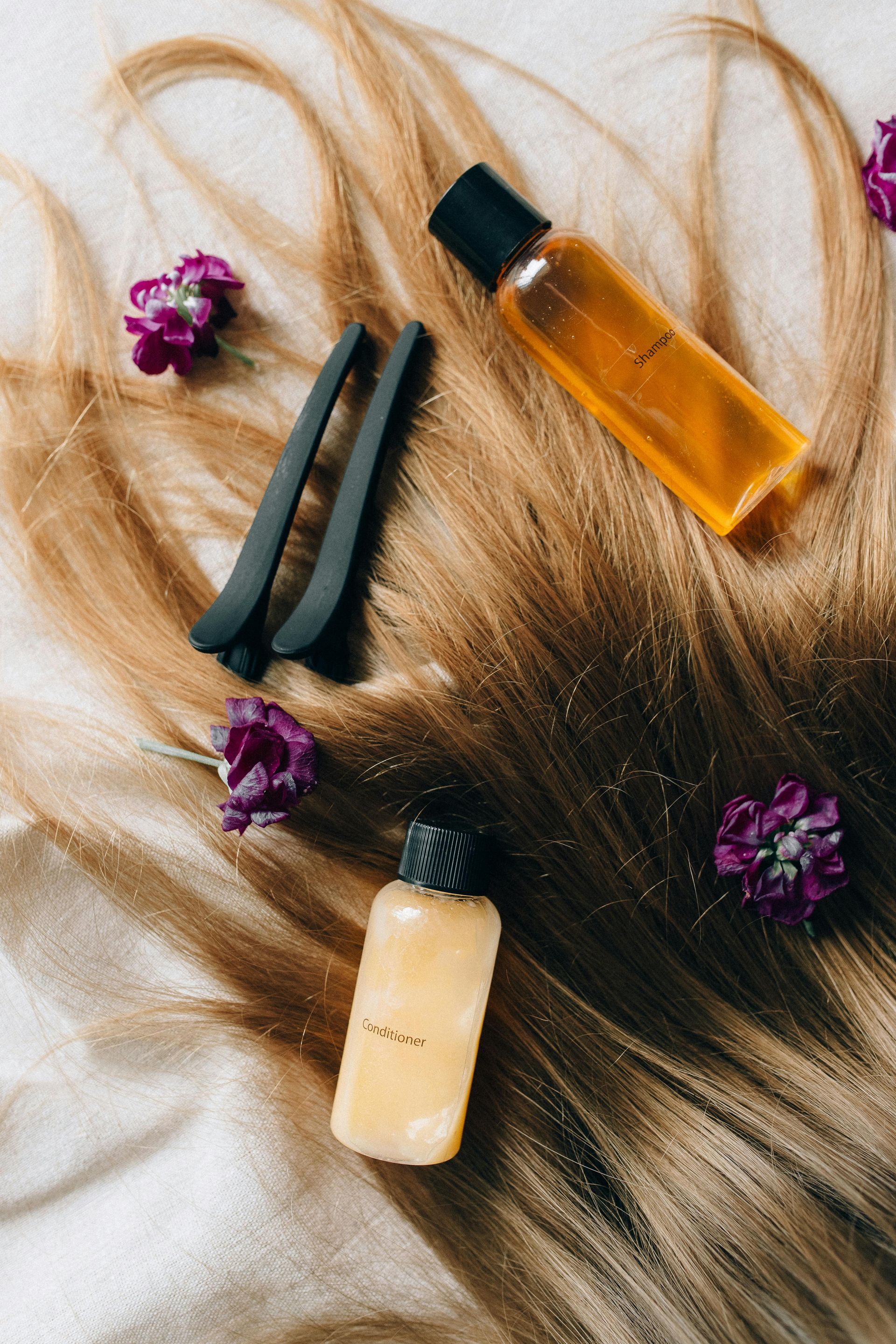 Hair care products and clips on blond hair with purple flowers.