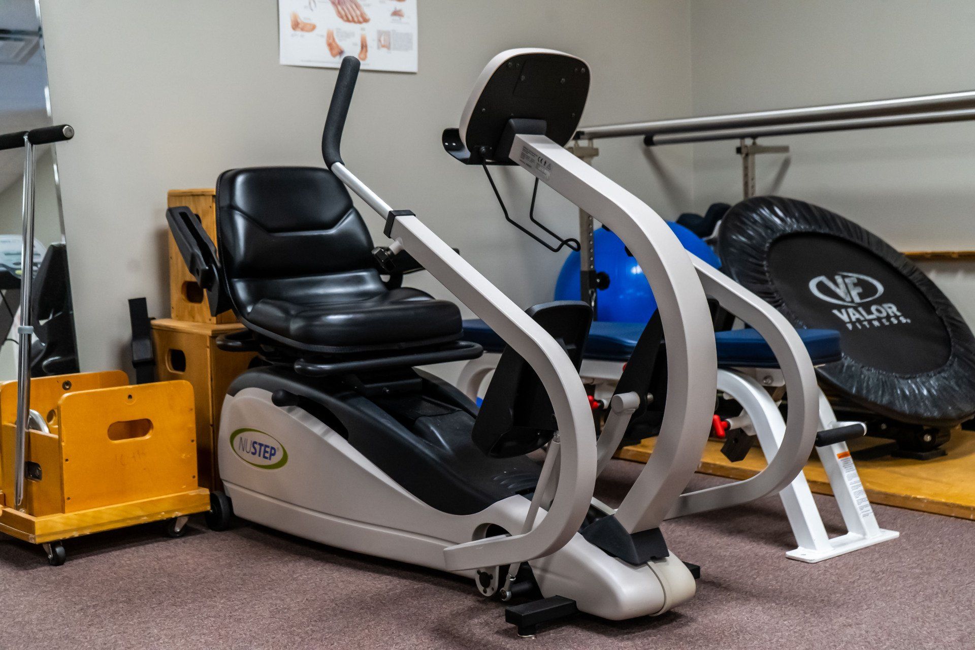 a recumbent exercise bike is sitting in a room next to a trampoline .