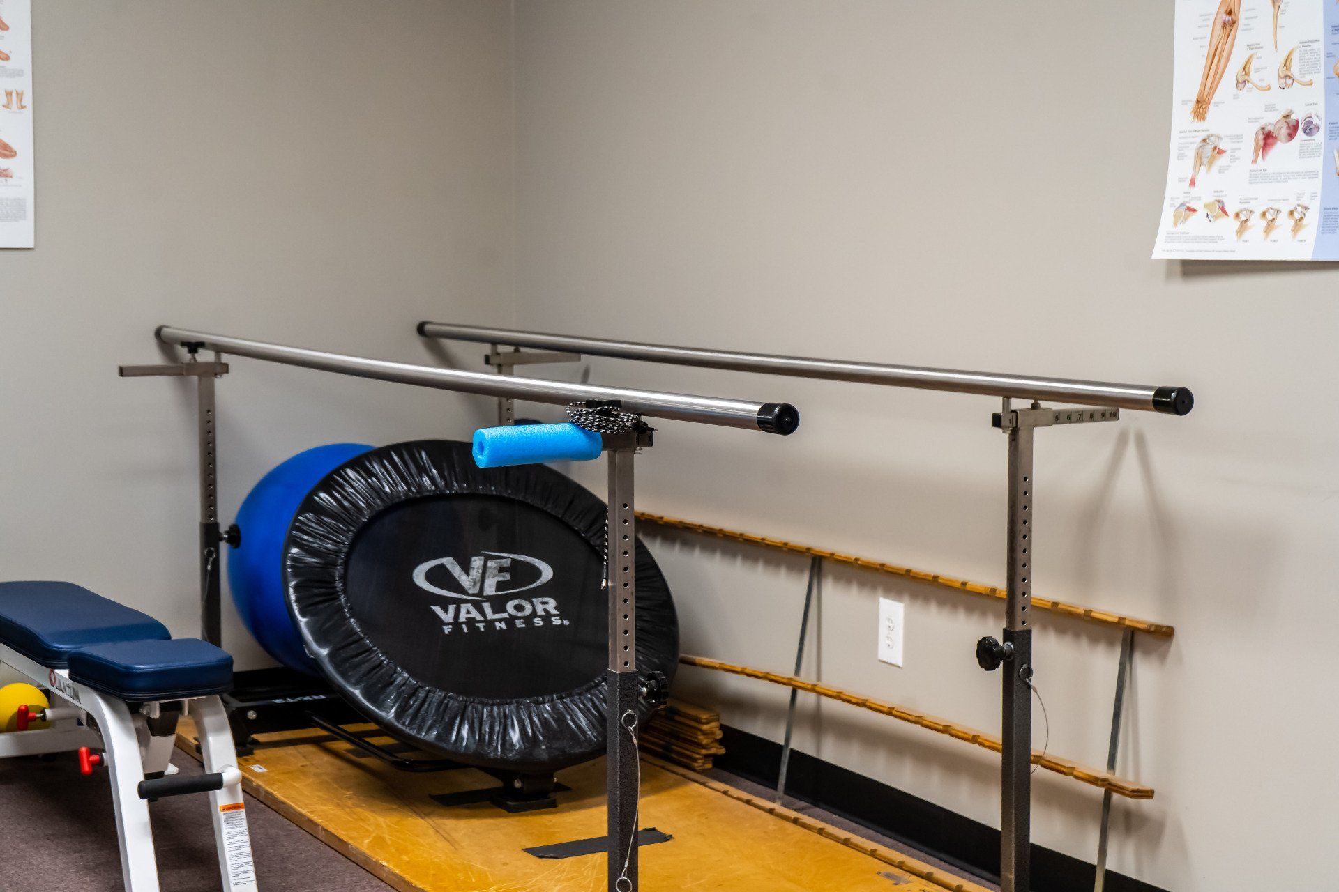 a room with a trampoline , bench , and parallel bars .