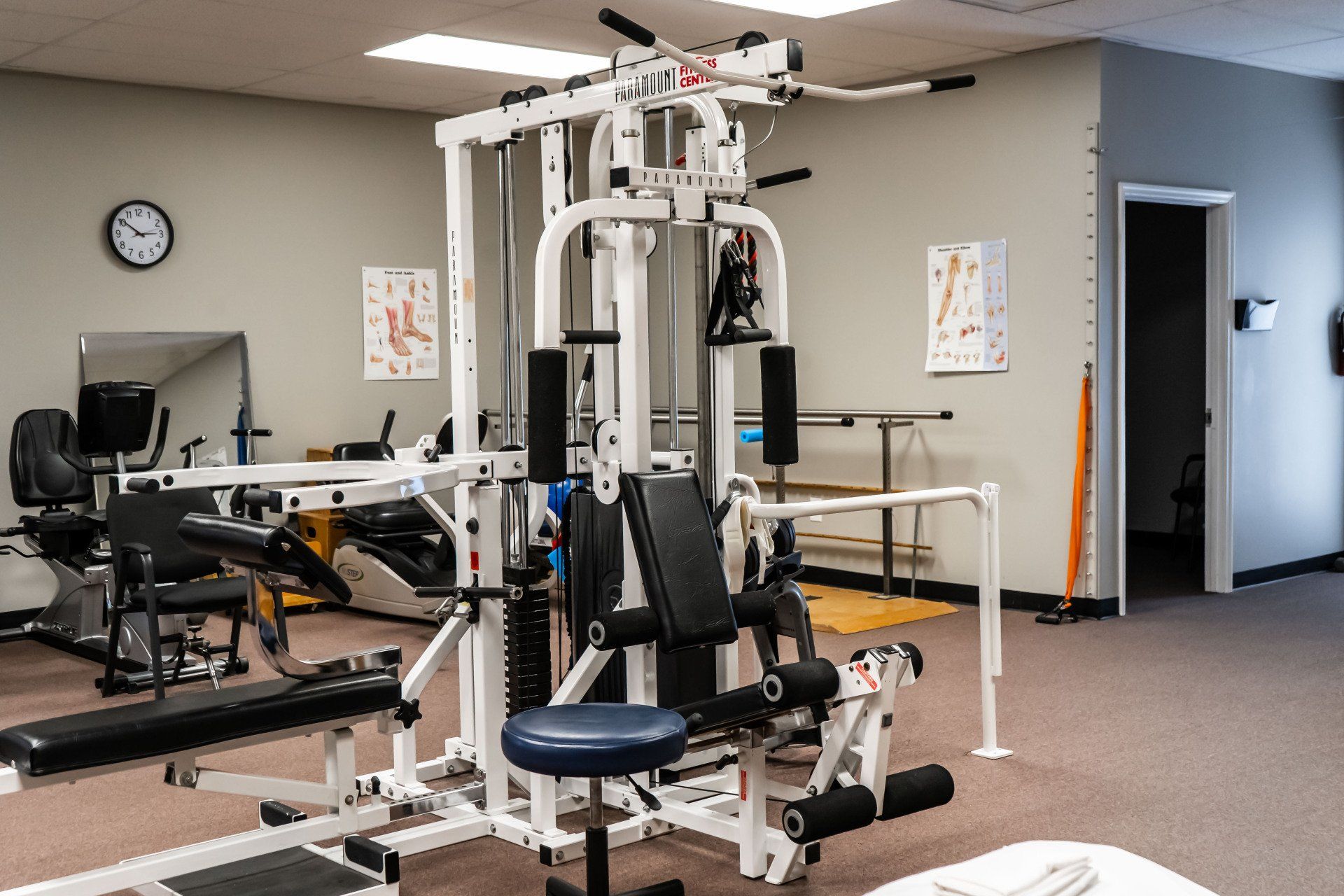 a gym with a lot of exercise equipment and a clock on the wall .