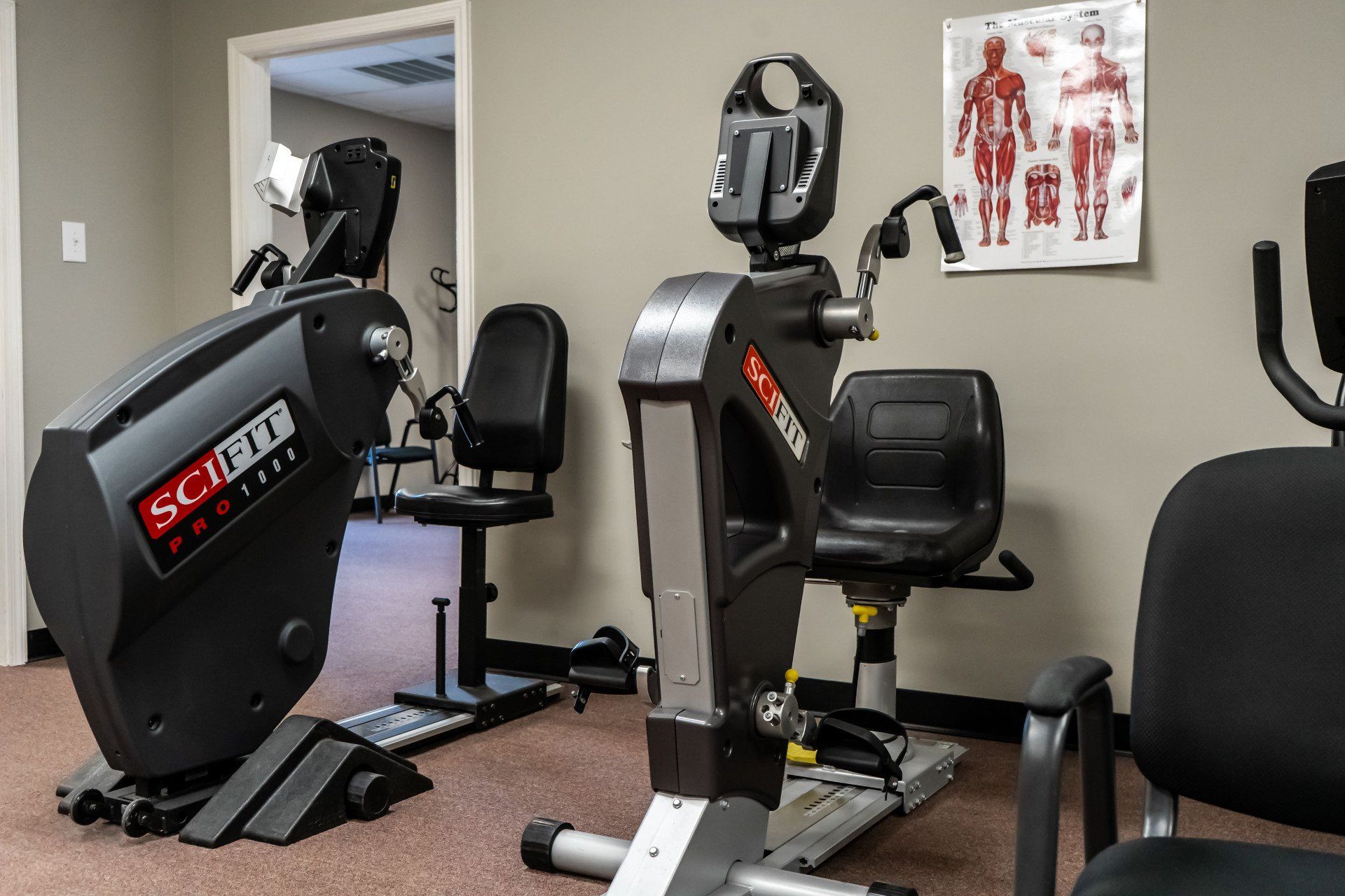 a room with exercise bikes and chairs in it