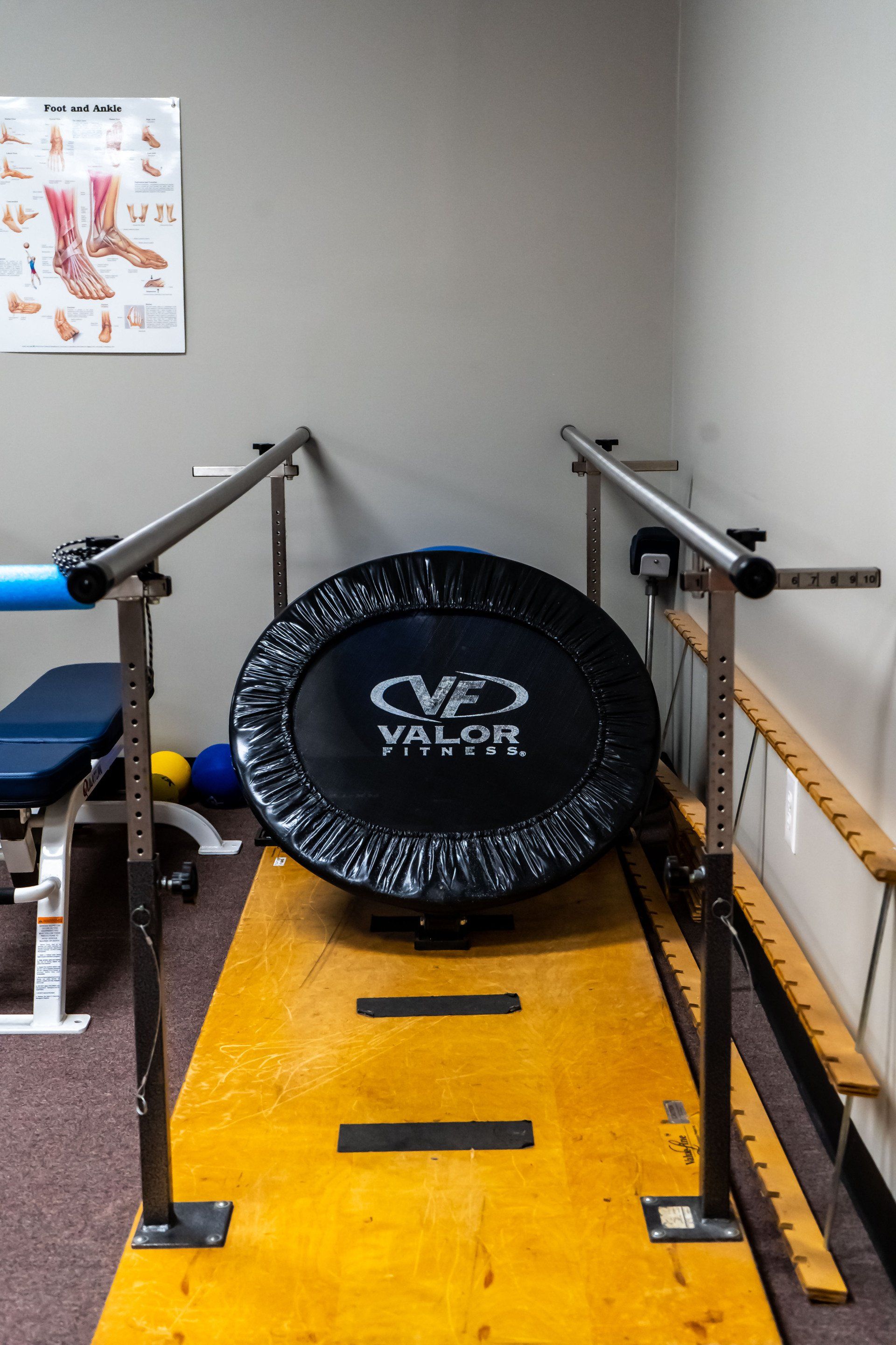 a trampoline is sitting on a wooden floor in a room with parallel bars .