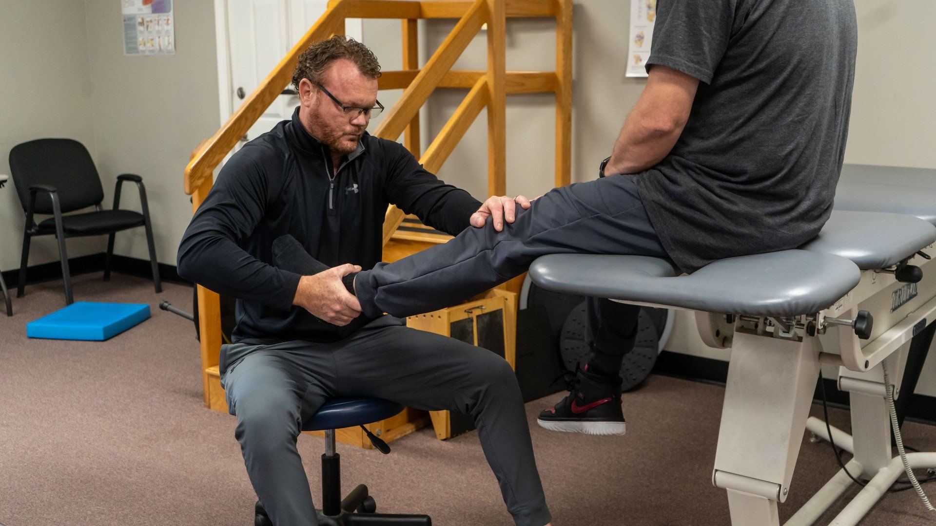 a man is examining another man 's leg on a table .