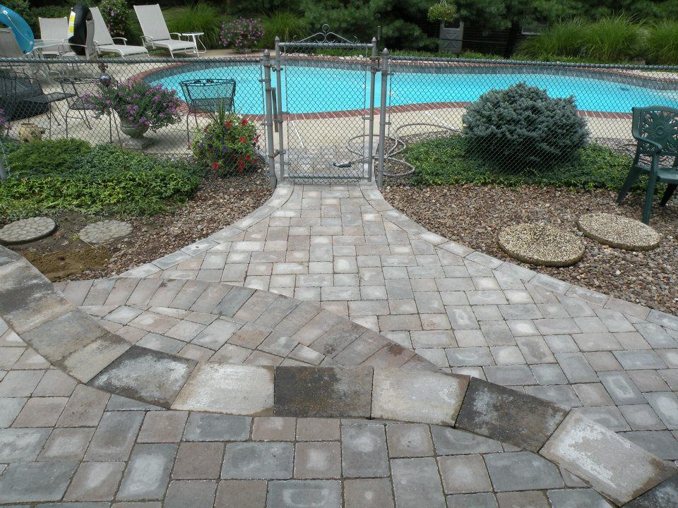 A brick walkway leading to a swimming pool