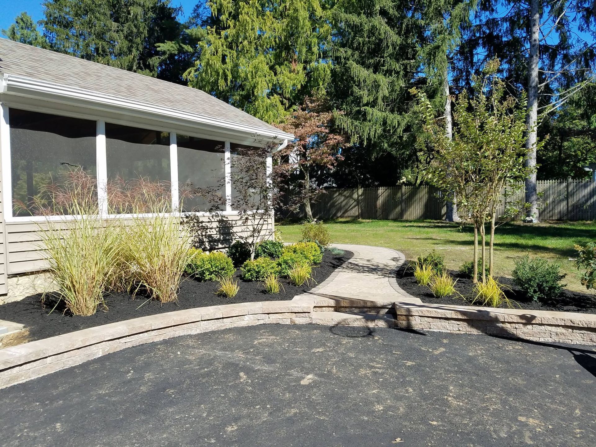 A house with a screened in porch and a walkway in front of it.