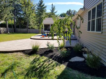 A backyard with a patio and a house in the background