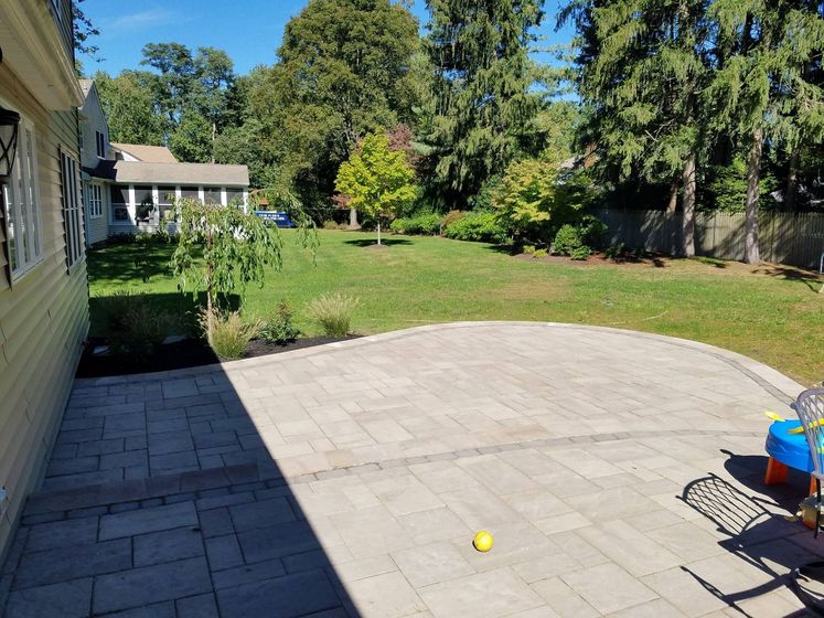 A backyard with a patio and a house in the background