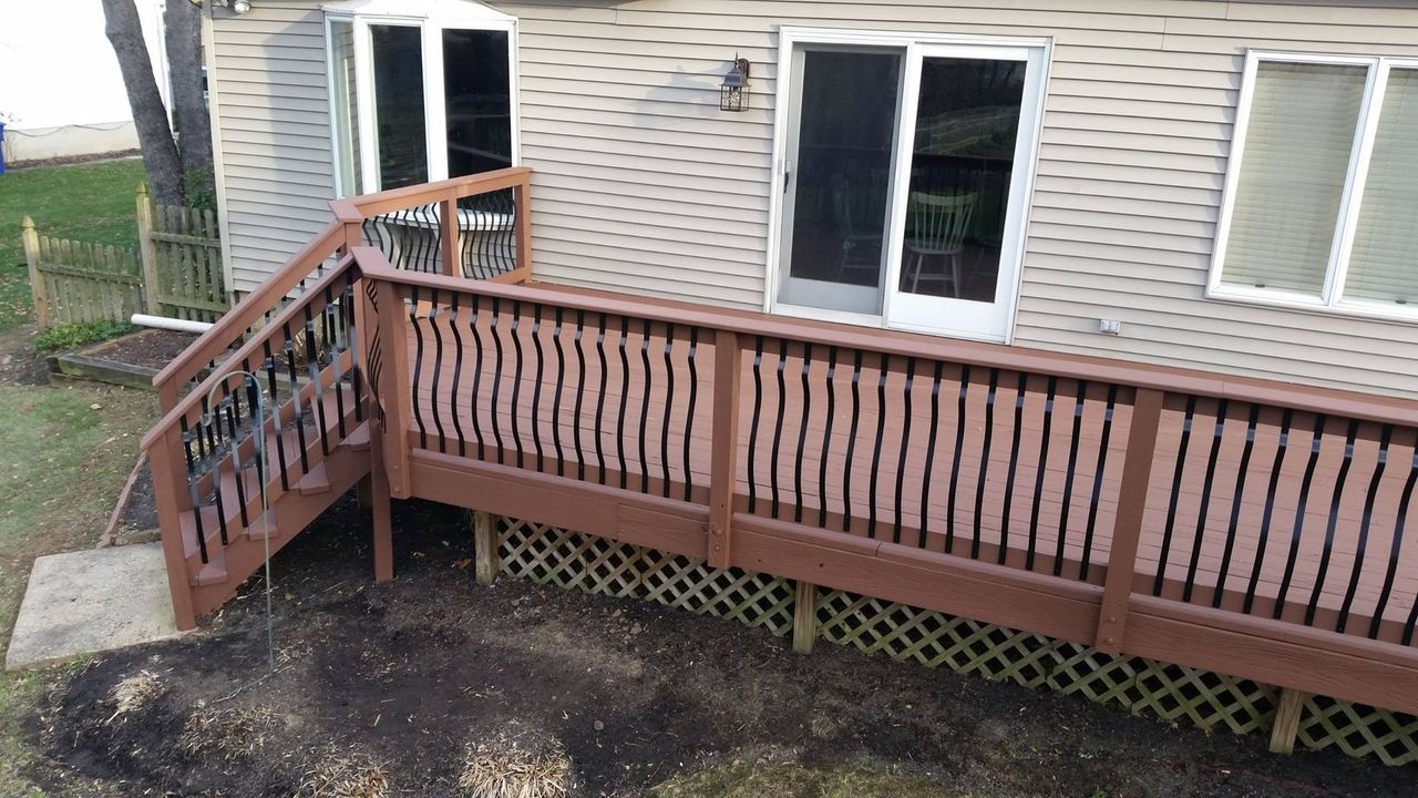 A wooden deck with stairs is in front of a house.