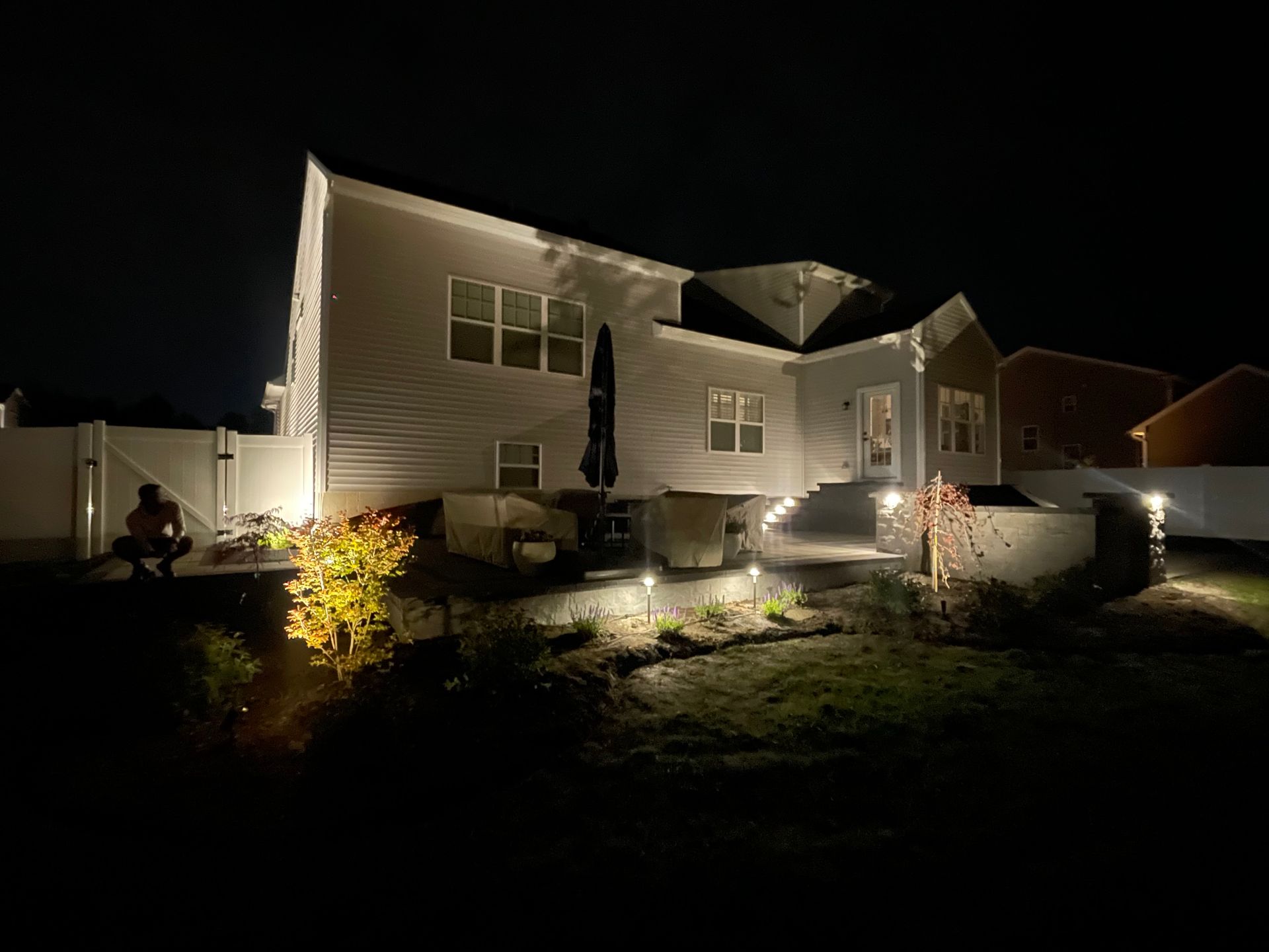 The backyard of a house is lit up at night.
