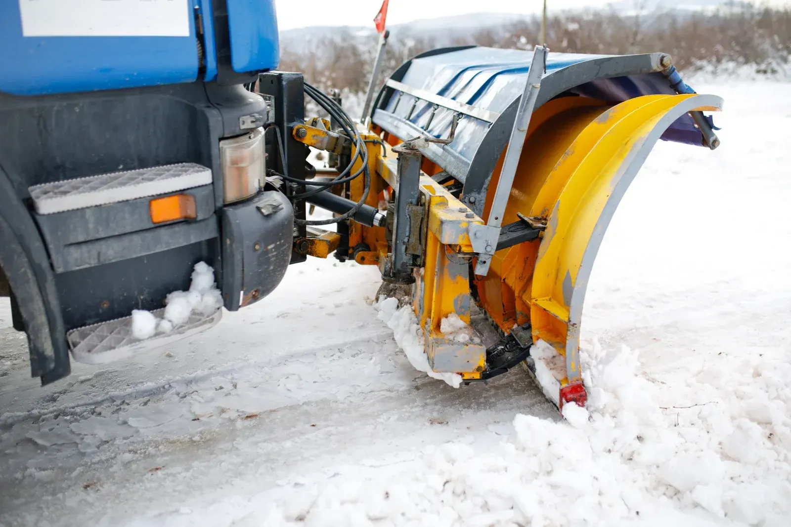 A snow plow is plowing snow on the side of a road.
