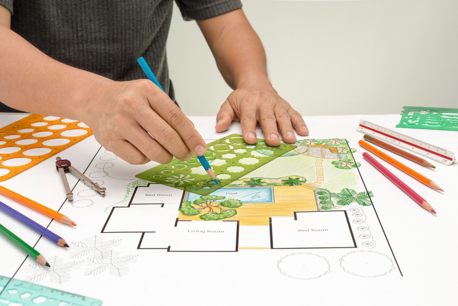 A man is drawing a picture of a garden on a piece of paper.