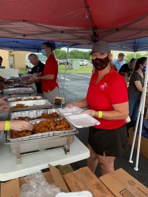 A woman wearing a mask is holding a tray of food.