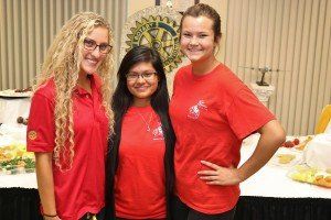 Three women wearing red shirts are posing for a picture.