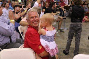 A man is holding a baby in his arms in front of a crowd.