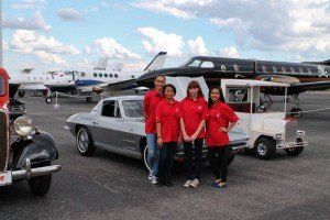 A group of people standing in front of an airplane and a car