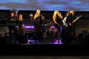 A group of people are standing on a stage singing into microphones.