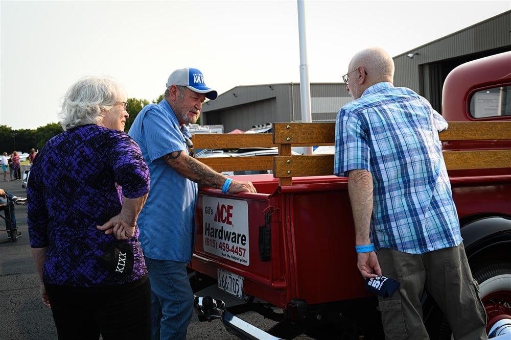 A group of people are standing around a red truck.