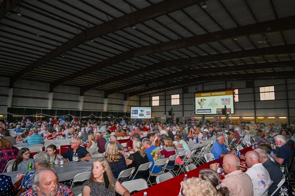 A large group of people are sitting at tables in a large building.