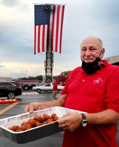 A man in a red shirt is holding a tray of food