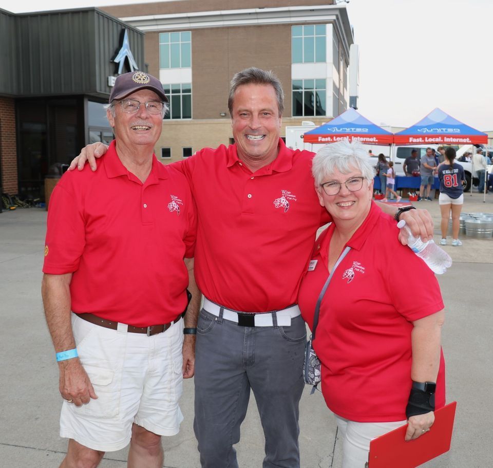 Three people in red shirts are posing for a picture