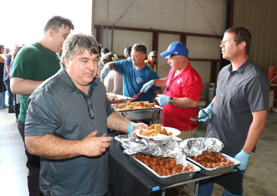 A group of men are standing around a table eating food