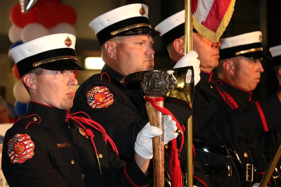 A group of men in uniform holding flags and a hammer