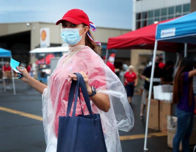 A woman wearing a mask and a poncho is walking down the street