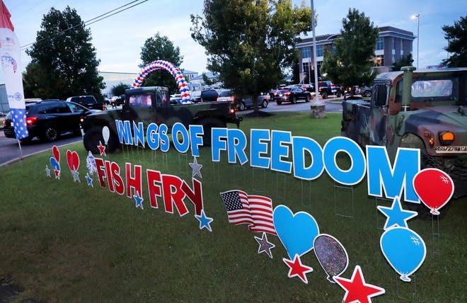 A jeep is parked in front of a sign that says wings of freedom