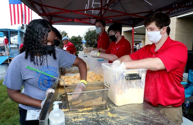 A group of people wearing face masks are standing around a table.
