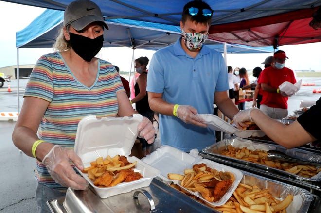 A man and a woman wearing face masks are getting food from a buffet.