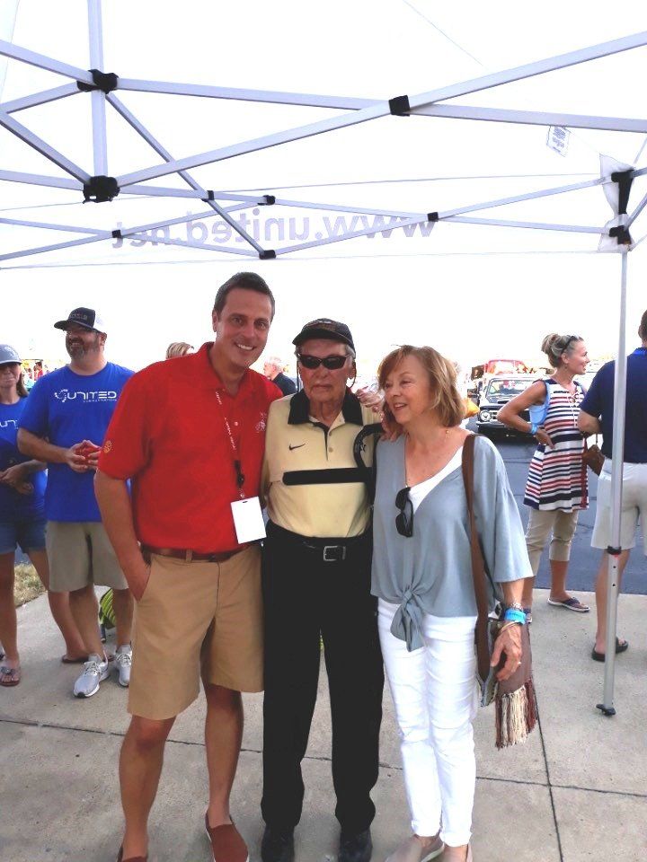 A man in a red shirt is posing with two other people