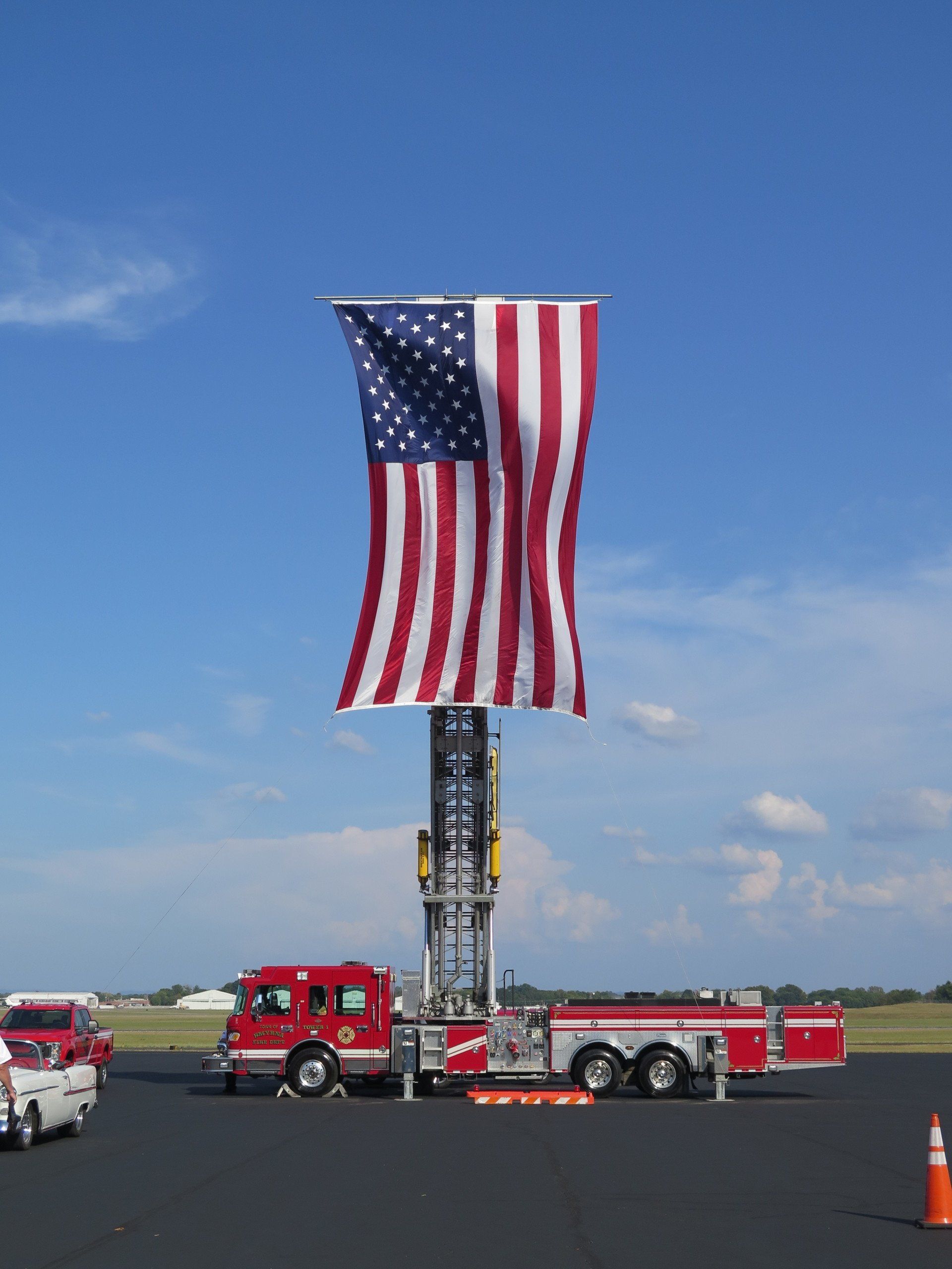 A large american flag is hanging from the top of a fire truck
