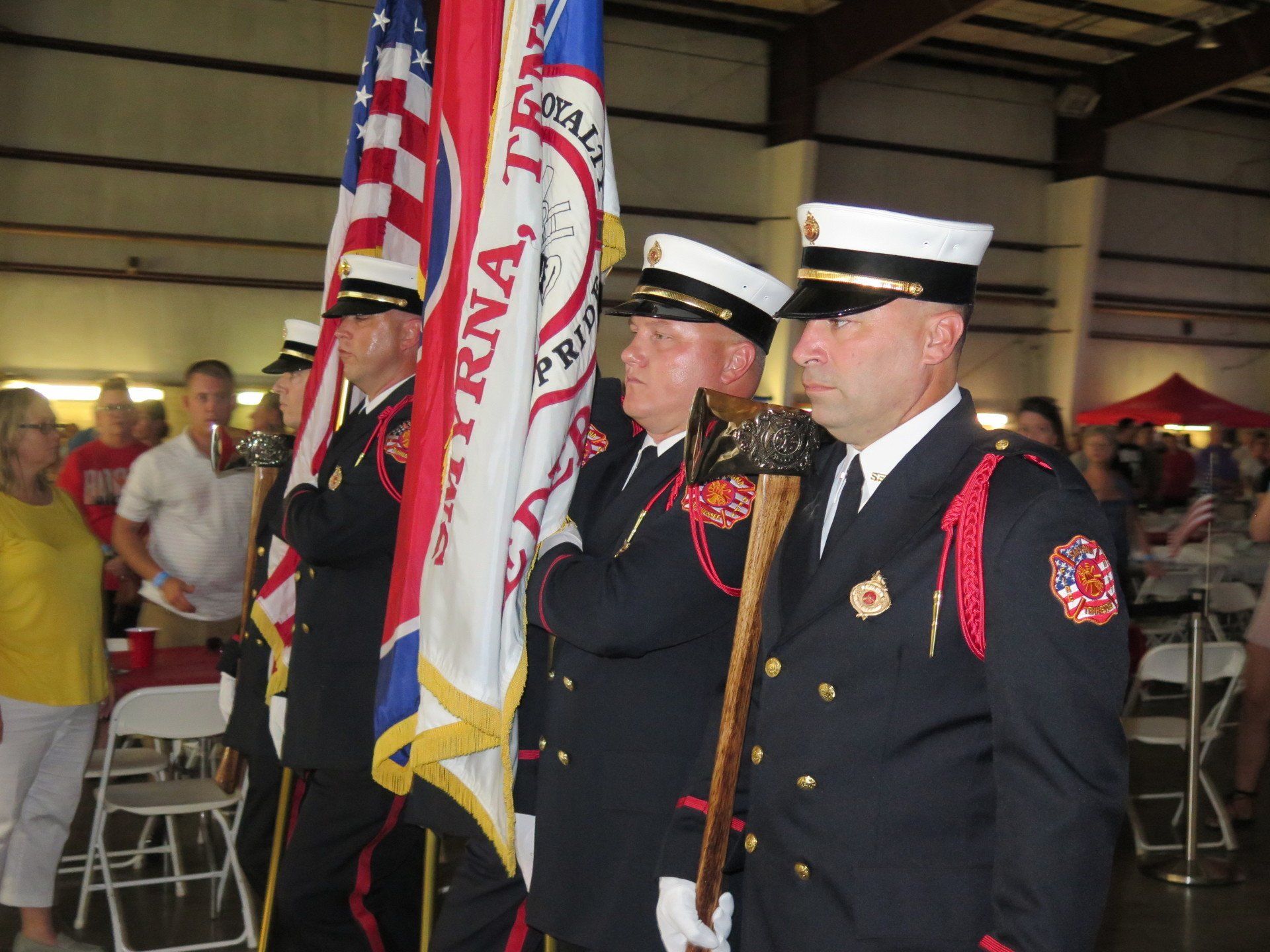 A group of firefighters holding flags in a room