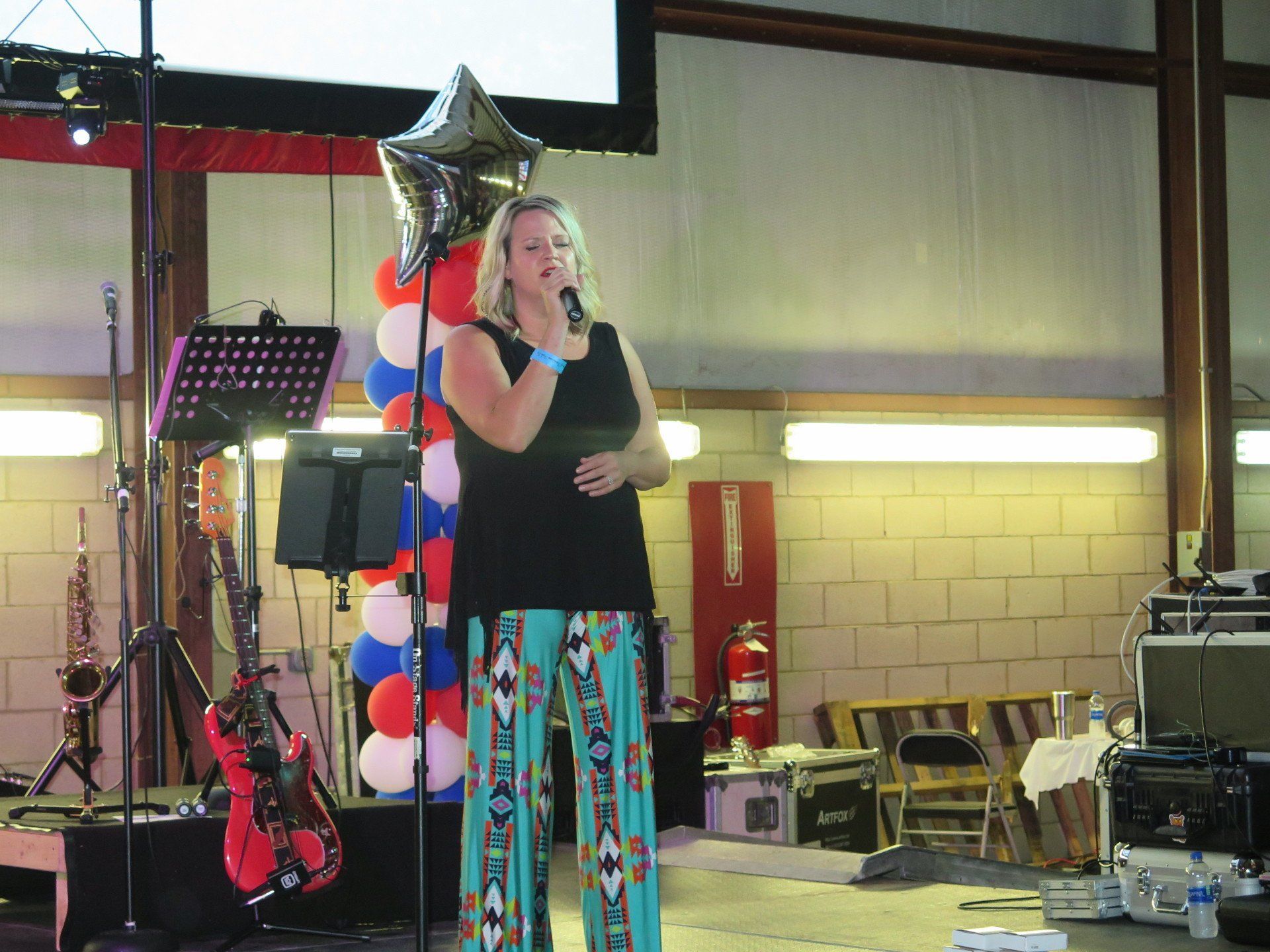A woman singing into a microphone with balloons in the background