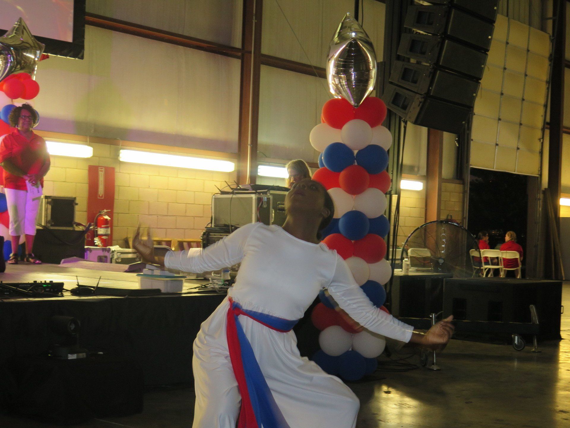 A man is dancing on a stage with balloons in the background