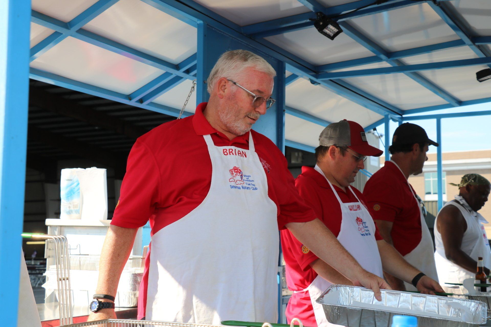 A man in a red shirt and white apron is standing in front of a counter