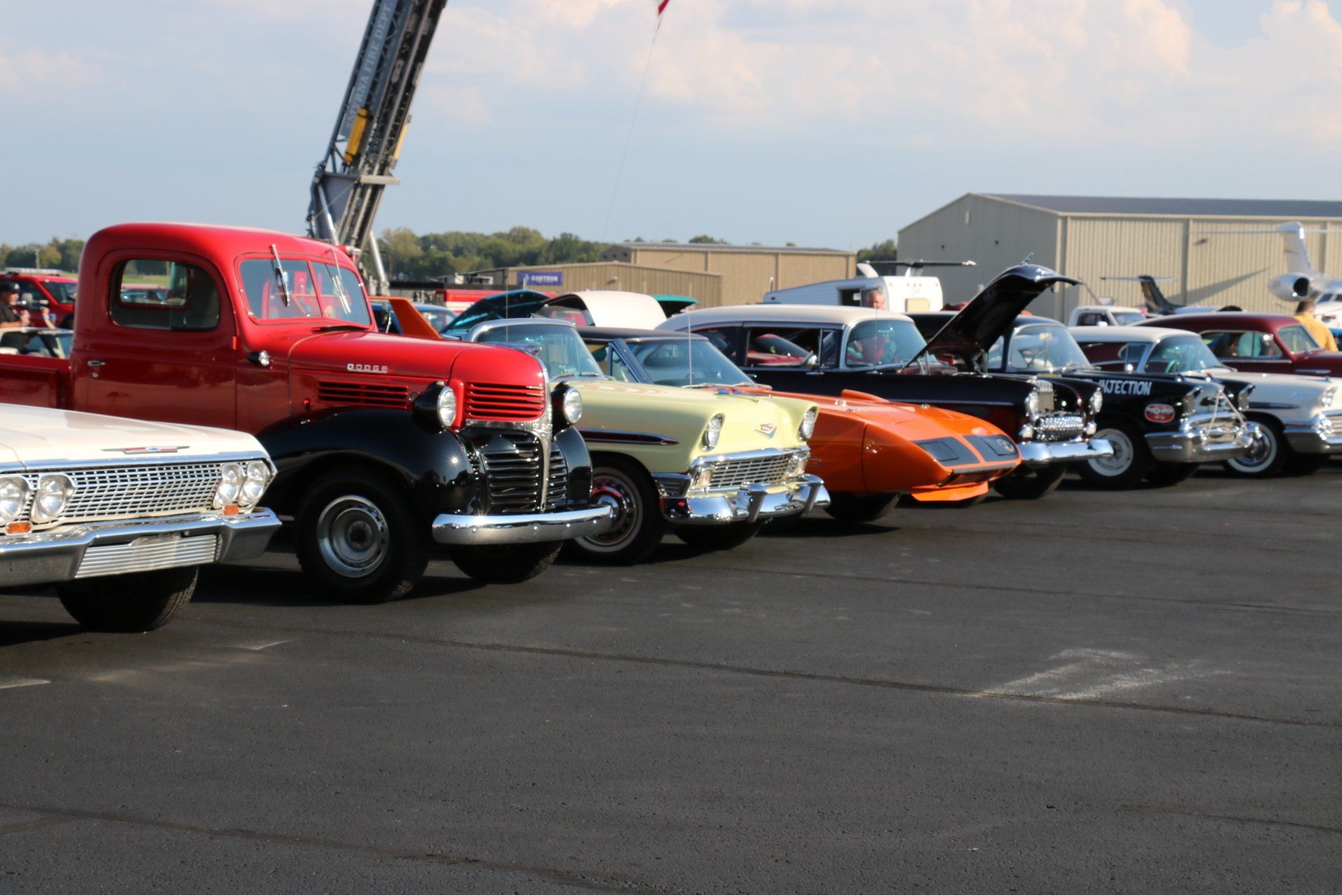 A row of old cars are parked in a parking lot