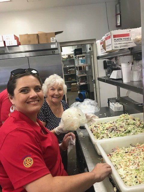 Two women are standing in a kitchen preparing food.