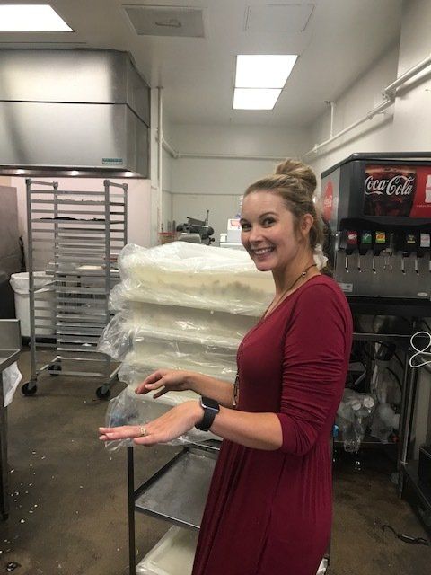A woman in a red dress is holding a stack of plastic bags in a kitchen.