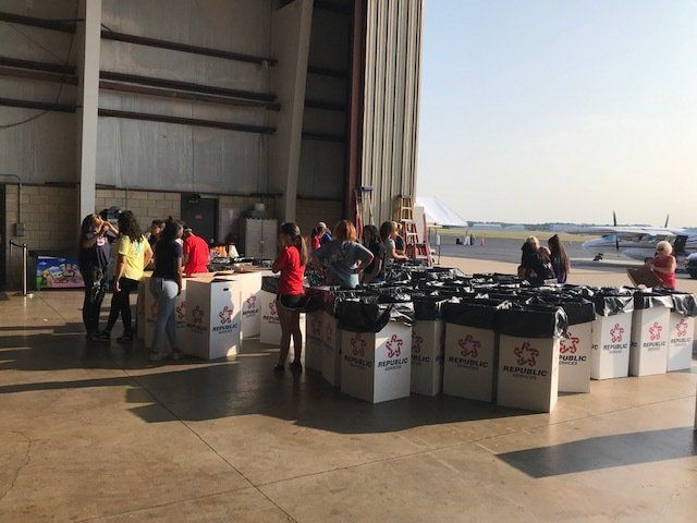 A group of people are standing in front of a large warehouse filled with boxes.