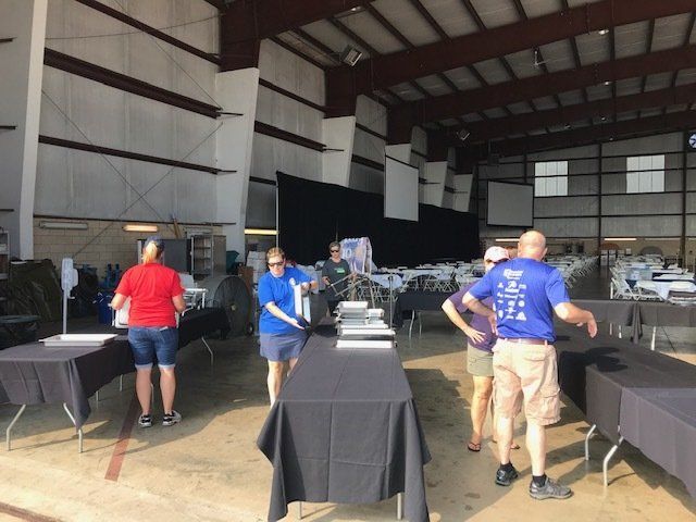 A group of people standing around tables in a large room