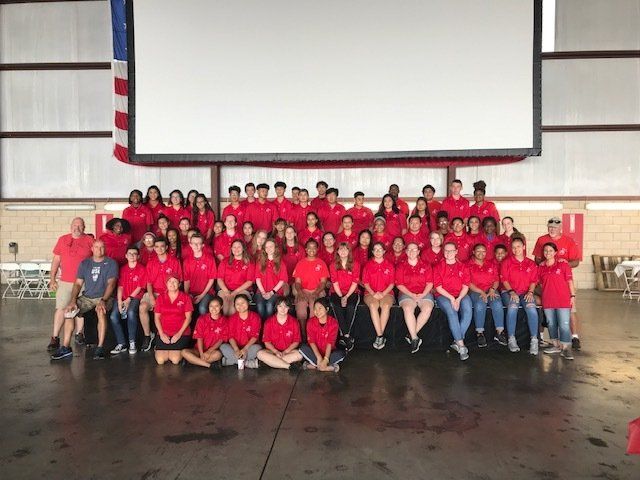 A large group of people in red shirts are posing for a picture