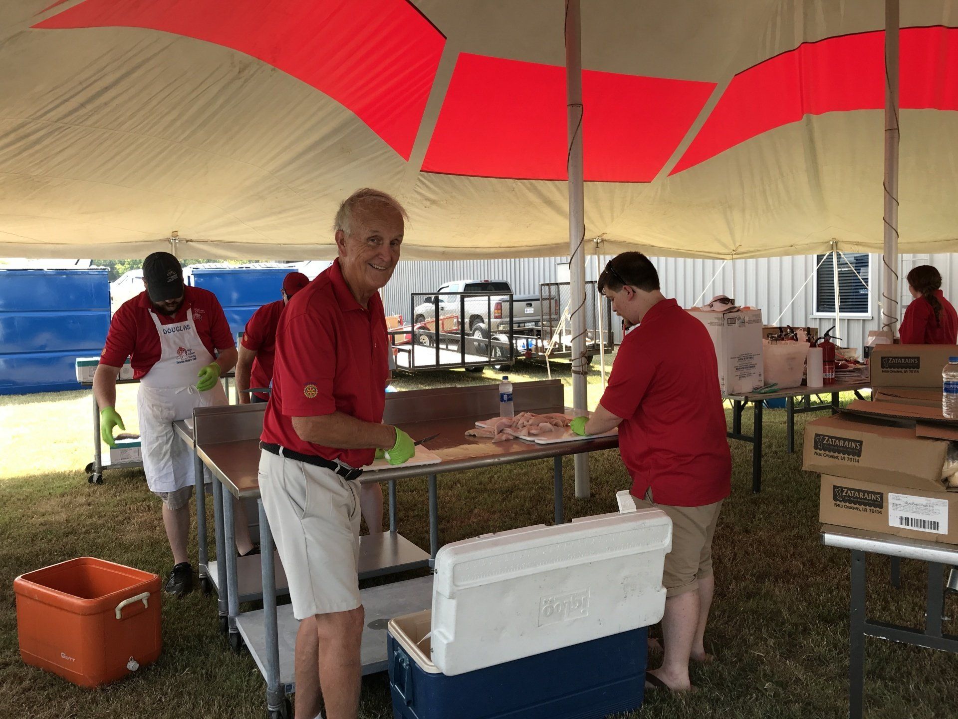 A group of people are standing around tables under a tent.