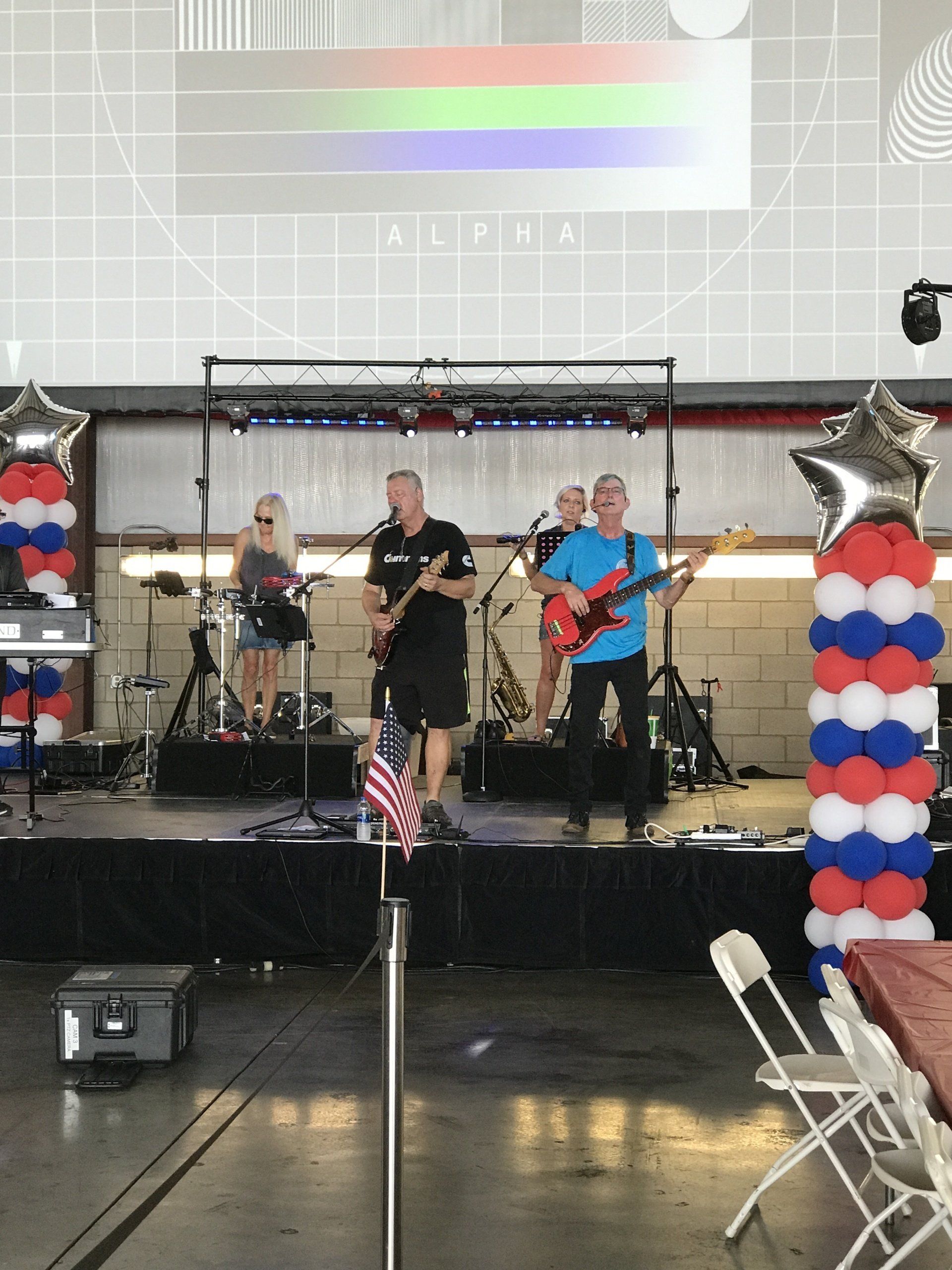 A band is playing on a stage with red white and blue balloons