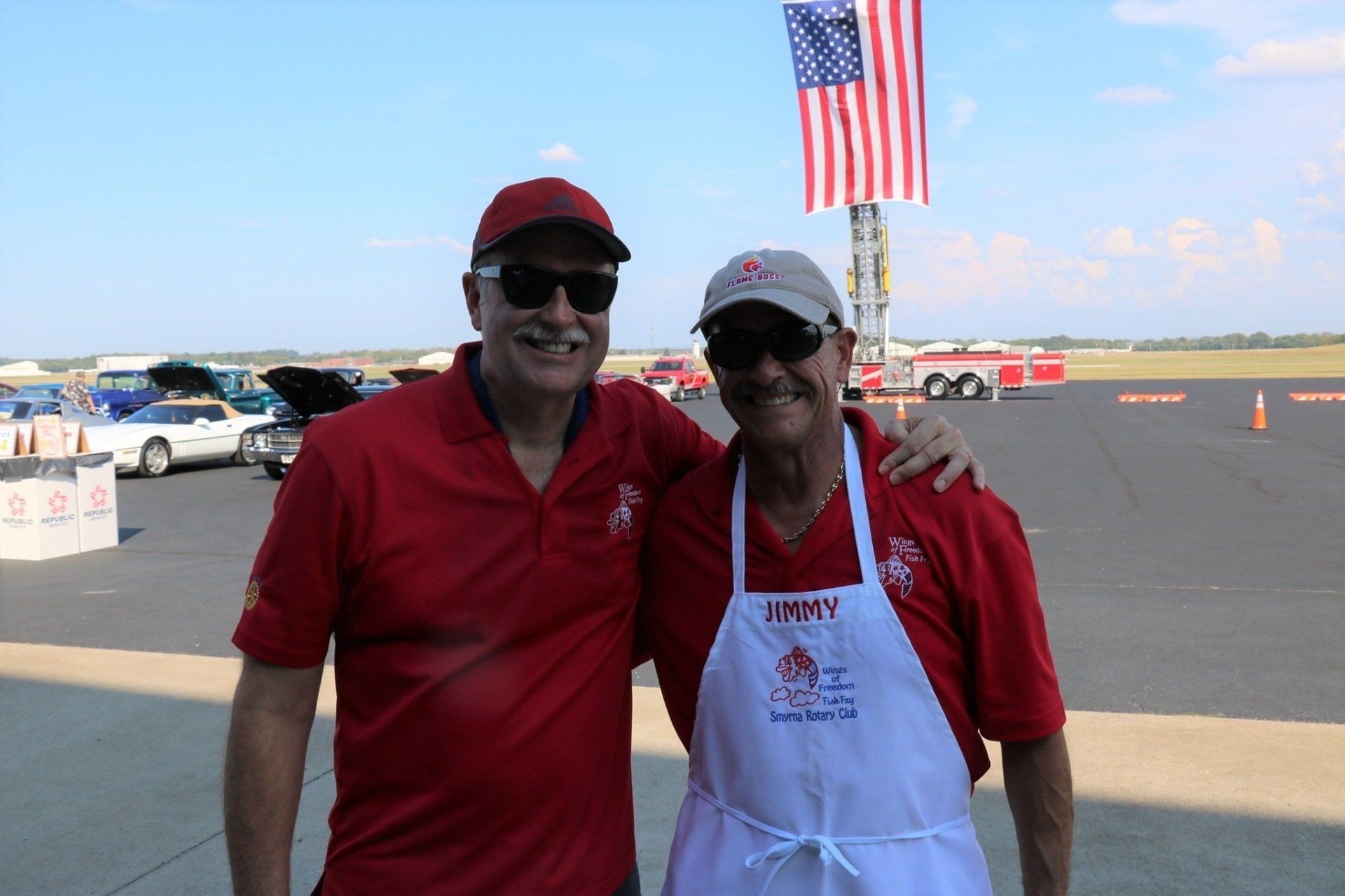 Two men are posing for a picture in front of an american flag