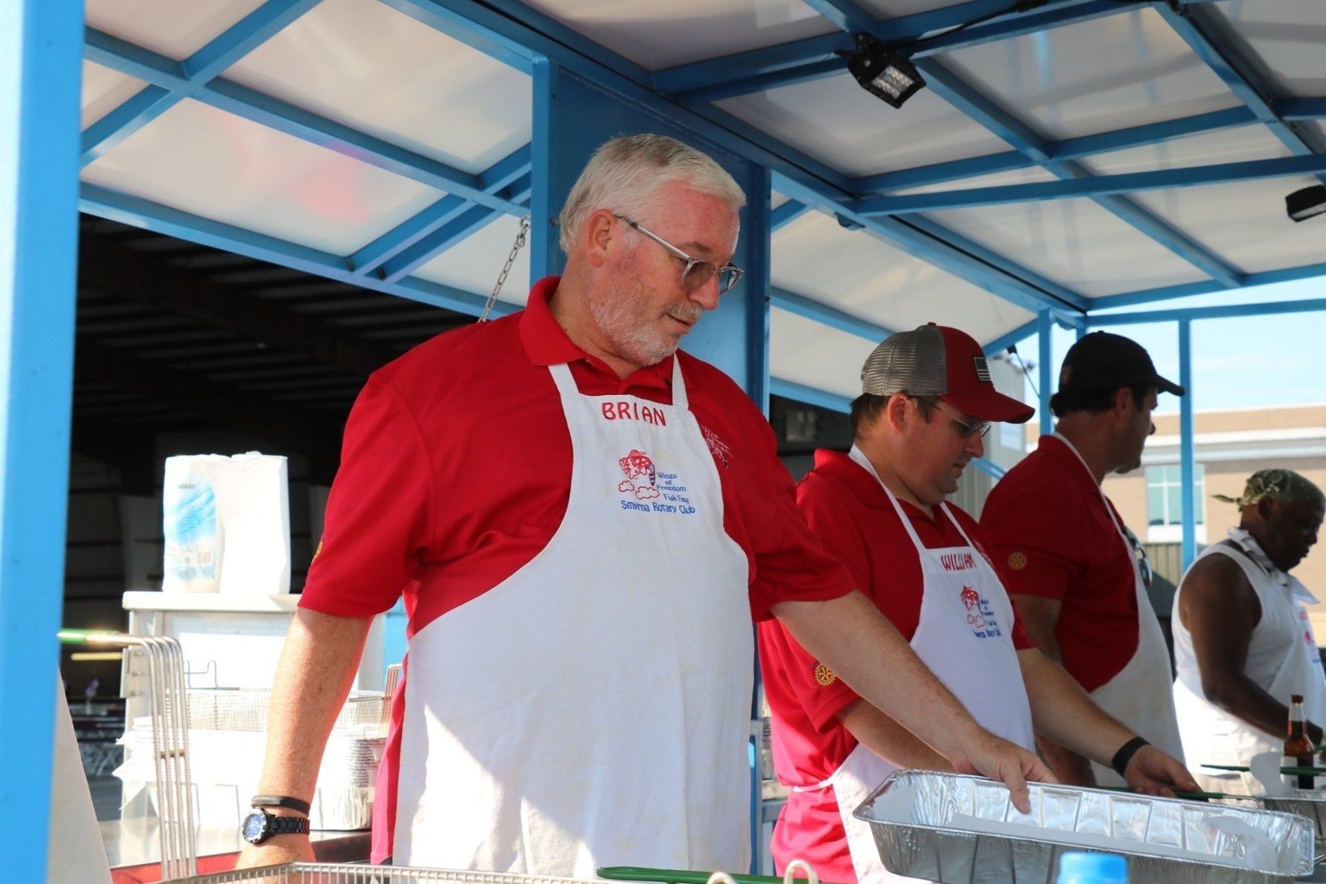 A man in a red shirt and white apron is standing in front of a counter