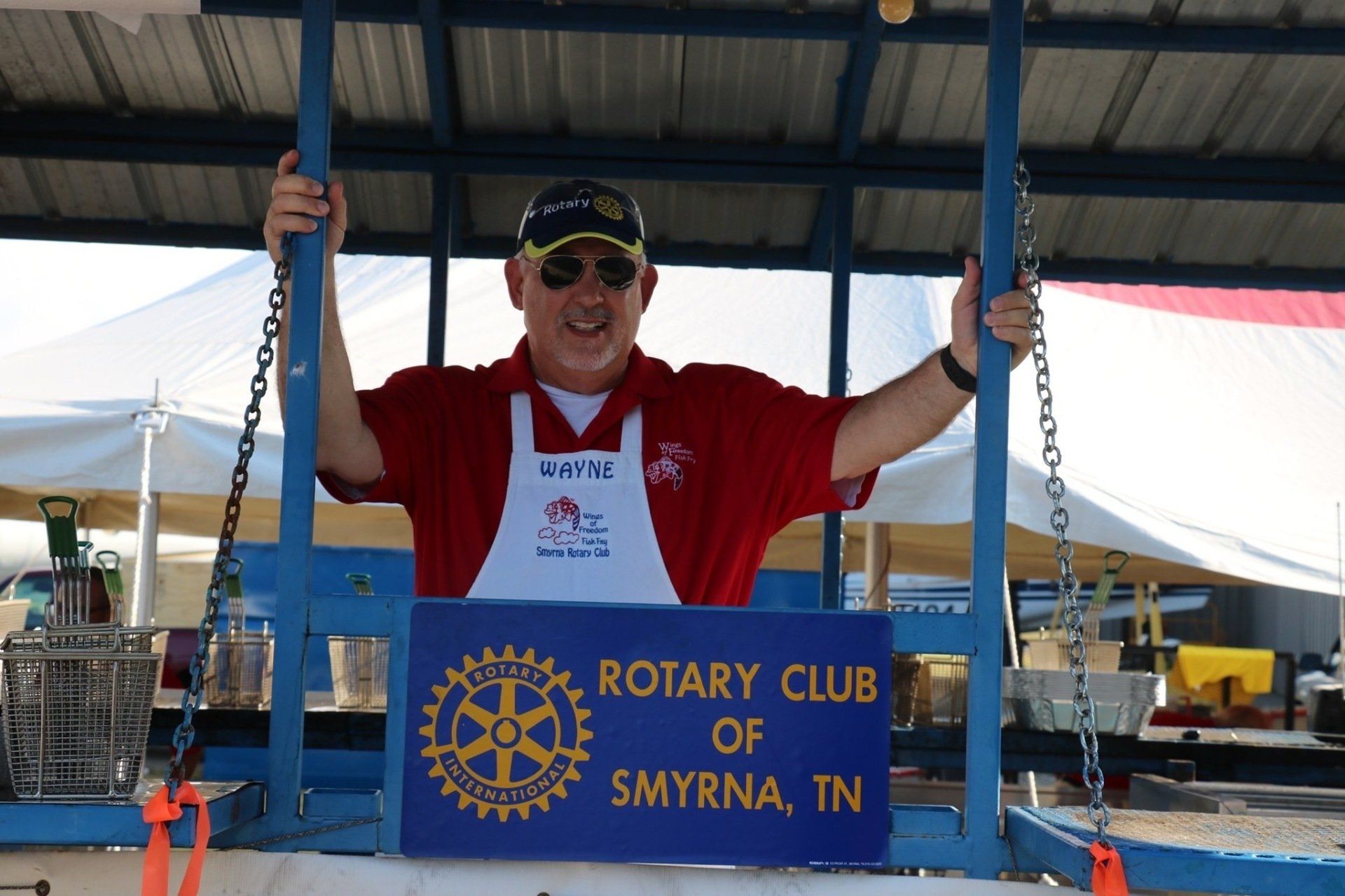 A man stands behind a sign that says rotary club of smyrna tn